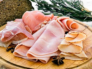 Verschiedene Schinkensorten liegen auf einem Holzbrett.