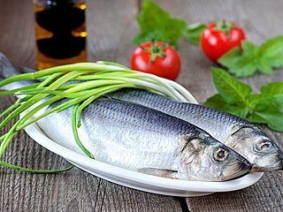 Zwei Fische auf einem Teller, mit Gemüse garniert.