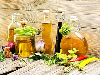 Mehrere Glasflaschen gefüllt mit verschiedenen Essigsorten. 