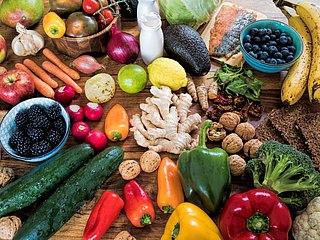 Ein Tisch mit einer Vielzahl an verschiedenen Obst- und Gemüsesorten wie Heidelbeeren, Karotten, Äpfel, Broccoli, Paprika und weiteren Sorten.