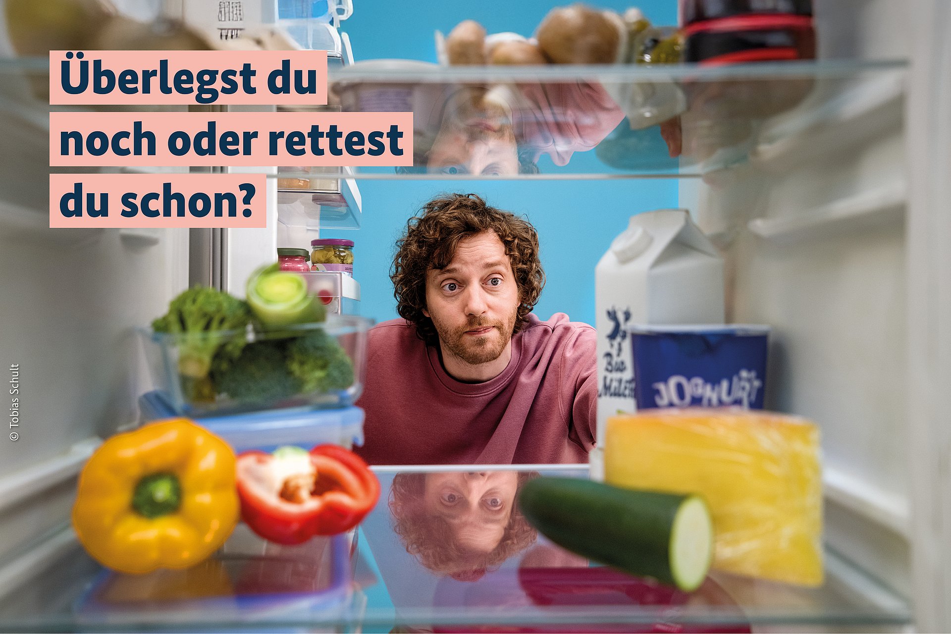 Mann schaut fragend in einen Kühlschrank voller angebrochener Lebensmittel. 