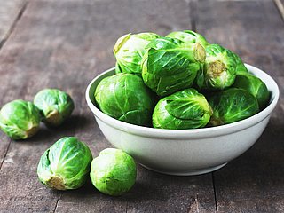 Rosenkohl-Röschen liegen in einer Schüssel. Daneben liegen weitere Röschen.