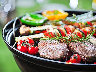 Fleisch und Gemüse liegen auf einem Grill. 