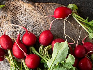 Mehrere Radieschen liegen auf einem Holzbrett.