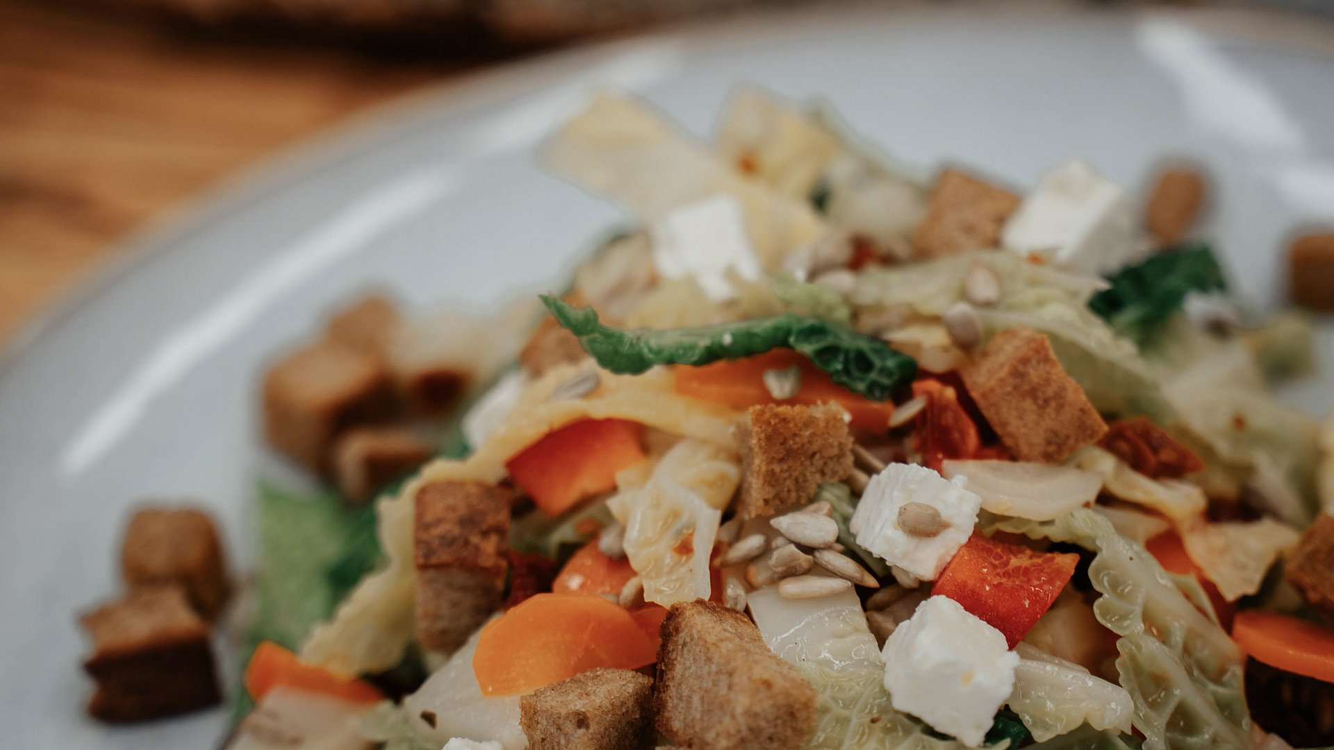 Nahaufnahme eines Salates aus Brotwürfeln, Gemüse und Körnern