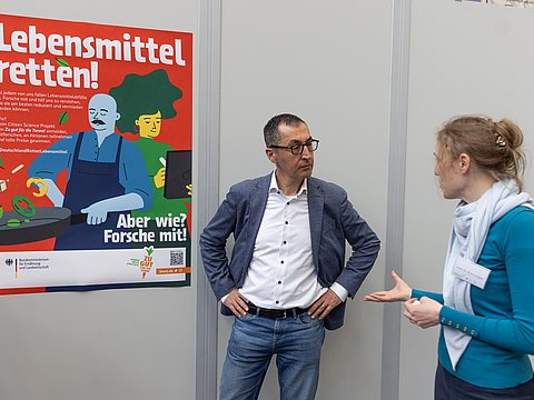 Bundesminister Cem Özdemier und Prof. Dr. Nina Langen (TU Berlin) im Gespräch. Im Hintergrund ein Poster des Citizen Science Projekts.
