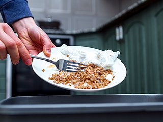 Essensreste vom Teller werden in den Müll geworfen.