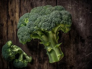 Ein Strunk Brokkoli und ein Röschen liegen auf einem Holzbrett. 