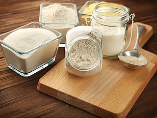 Mehl und verschiedene andere Backzutaten präsentiert in Glasbehältern.