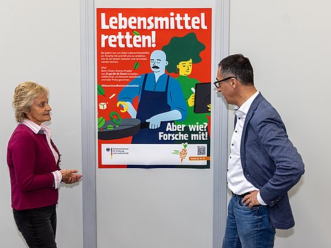 Andrea Lenkert-Hörrmann (Slow Food) und Bundesminister Cem Özdemier blicken auf ein Poster des Citizen Science Projekts.