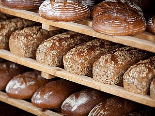 Mehrere verschieden Laibe Brot in einem Regal.