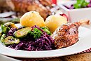 Teller mit Weihnachtsmenü, Rotkohl, Klöße, Rosenkohl und Gänsekeule