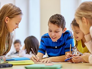 Kinder, die an Schulaufgaben arbeiten und lachen