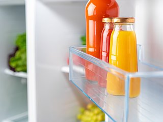 Mehrere Saftflaschen stehen in einer Kühlschranktür. 