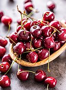 Kirschen liegen in einer Holzschale.