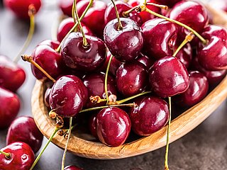 Kirschen liegen in einer Holzschale.