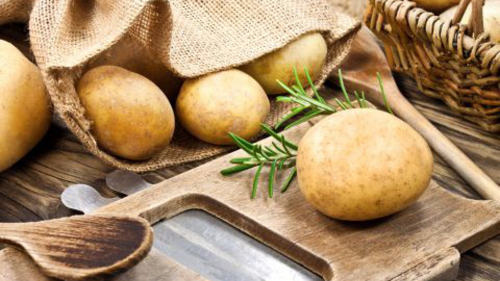 Frische Kartoffeln auf Holzbrett, in Jutebeutel und Korb
