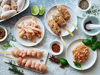 Verschiedene Geflügelgerichte werden neben Gewürzen präsentiert.