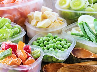 Verschiedenes Tiefkühlgemüse und -obst wird in Plastikschüsseln präsentiert.