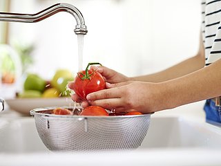 Eine Person wäscht Tomaten in der Küche.